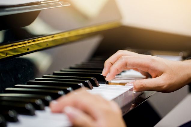 Selective focus image of a woman teaching a boy piano 